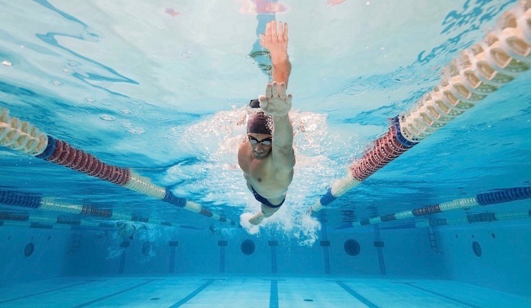 Professional man swimmer inside swimming pool. Underwater panoramic image.