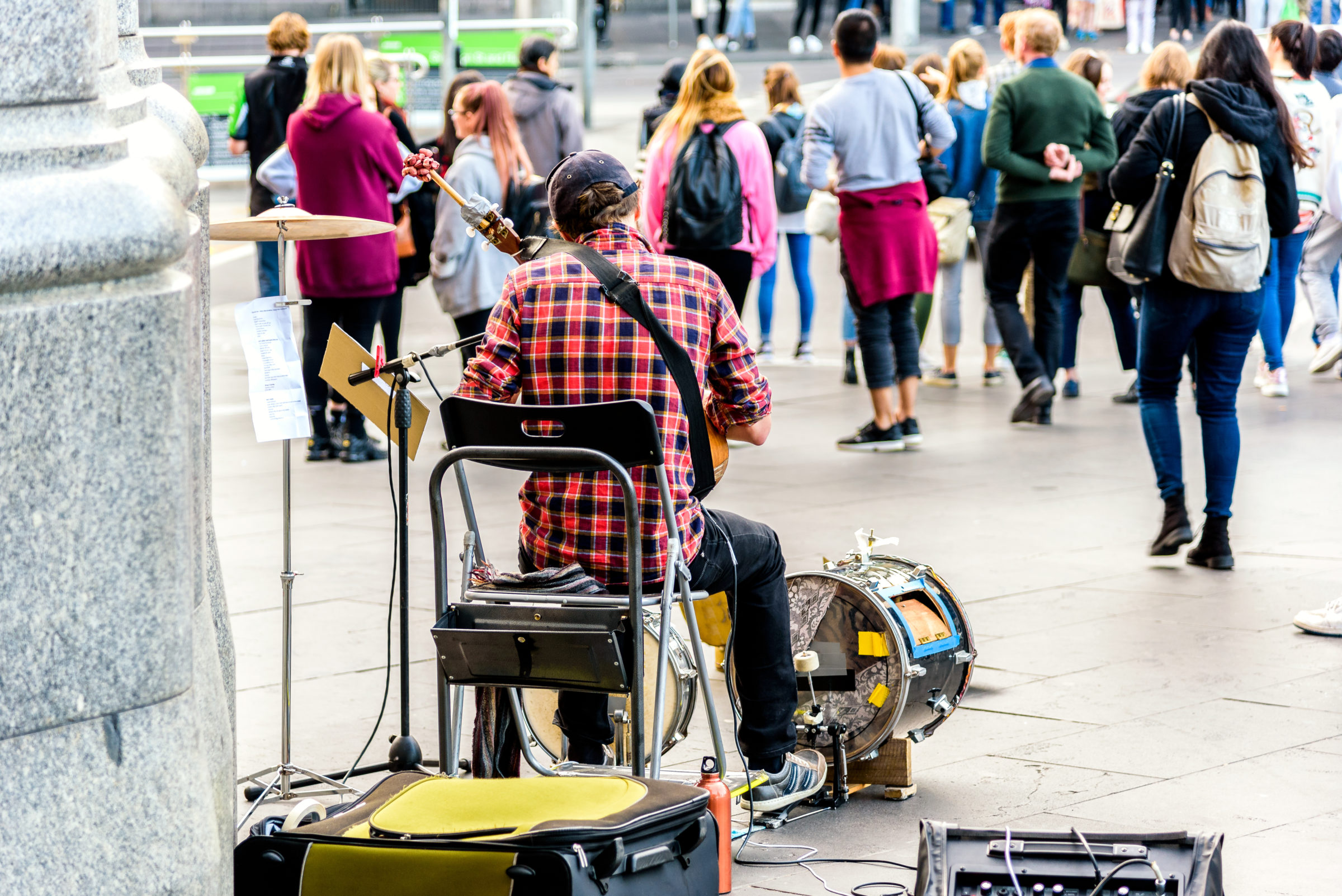 Melbourne, Victoria, Australia, May 26th 2018: A solo busker is sitting in front of the Flinders Street Train Station