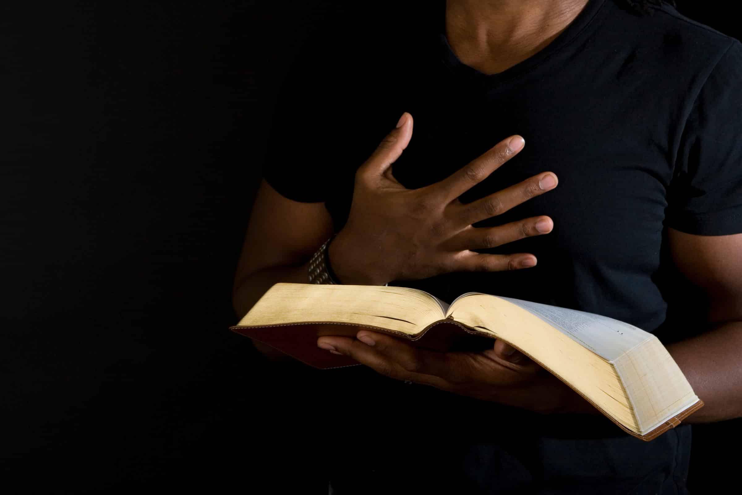 Man reading a bible isolated on black.